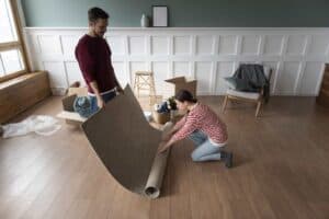 Couple unrolling a rug over hard wood floor